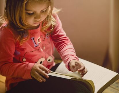 little girl flipping the page of a book