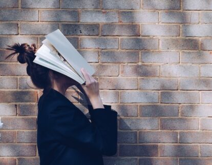 woman laying a book over her head while standing