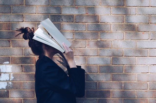 woman laying a book over her head while standing